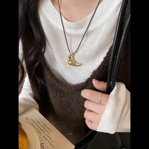 Dettaglio ravvicinato di un ciondolo croissant d'oro su una collana di cordino nero