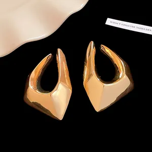 Detailed close-up of irregular geometric gold plated earrings on a black background