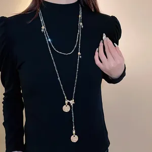 Detailed macro view of vintage gold bee and coin long necklace on black sweater