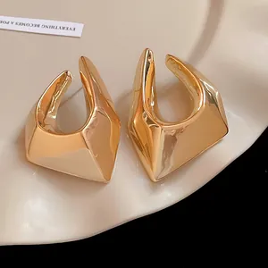 Close-up of gold-plated irregular geometric stud earrings with high-polish metallic finish.