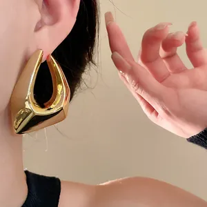 Detailed close-up of chunky irregular geometric gold-plated stud earrings on model