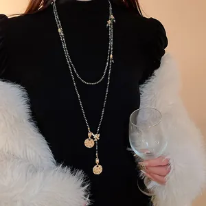 Detailed view of long vintage-style necklace with bee and gold coin charms on a model