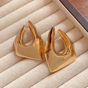 Macro detail of irregular chunky geometric gold plated earrings on cream velvet jewelry tray