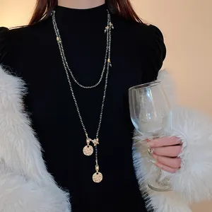 Detailed shot of vintage style gold coin and bee charm long beaded sweater necklace on model