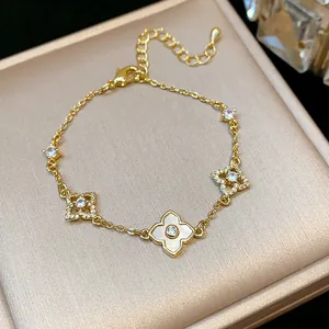 Close-up of gold-plated bracelet with mother-of-pearl floral charms and sparkling zircons
