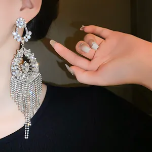 Close-up of elegant silver-needle flower drop earrings with long rhinestone tassels