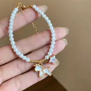 Close-up of elegant 18k gold plated pearl bracelet with unicorn and star charms