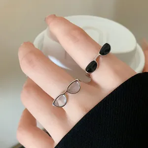 Close-up of unique silver rings shaped like eyeglasses with black and white lenses