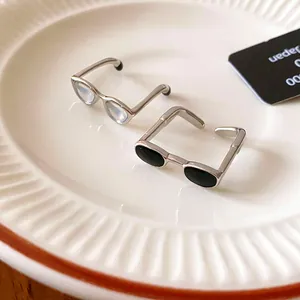 Macro view of minimalist spectacle-shaped open rings with black and clear drip oil