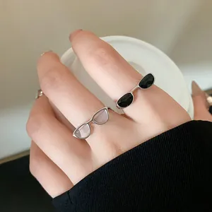 Close-up of unique silver glasses shaped open ring with black and clear enamel lenses