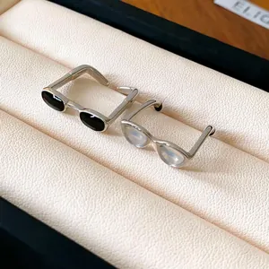 Detailed view of sunglasses shaped open rings with minimalist black and white enamel