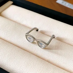 Detailed macro shot of a creative silver glasses-shaped open ring in a display box