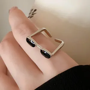 Detailed close-up of a minimalist silver-tone sunglasses shaped open ring with black enamel.