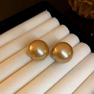 Primo piano di eleganti orecchini a lobo con perle color champagne in un cofanetto bianco