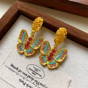 Macro view of vintage-style gold butterfly earrings with colorful sparkling rhinestones