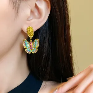 Macro detail of a vintage gold butterfly drop earring with inlaid colorful rhinestones.