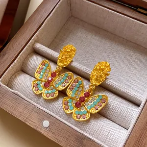 Detailed macro view of vintage butterfly earrings with colorful rhinestones in a wooden box