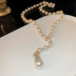 Dettaglio ravvicinato di una collana di perle a goccia stile francese con finiture dorate.