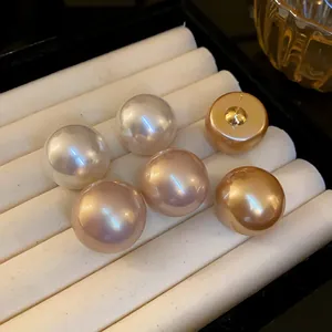Dettaglio degli orecchini a perno con perle vintage oversize in varie tonalità calde
