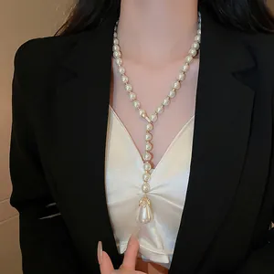 Dettaglio di una collana di perle con ciondolo a goccia di strass su una modella