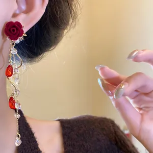 Macro view of vintage red flocking rose earrings with pearl and crystal tassels.