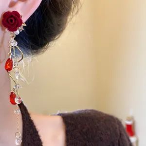 Close-up of a vintage red flocked rose earring with pearls and crystal tassels on a model
