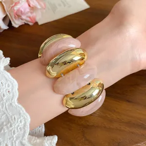 Close-up detail of a pink marbled acrylic and gold-tone metal chunky link bracelet on a wrist.