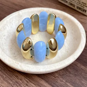 Macro view of a retro elastic bracelet featuring blue marbled acrylic and gold oval segments