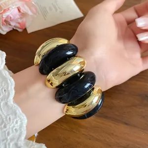 Elegant chunky acrylic bracelet featuring marbled black and gold-tone oval segments on wrist