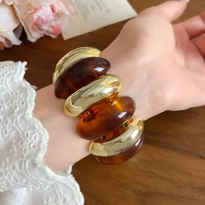 Close-up of a retro chunky bracelet with gold and amber marbled oval links on wrist