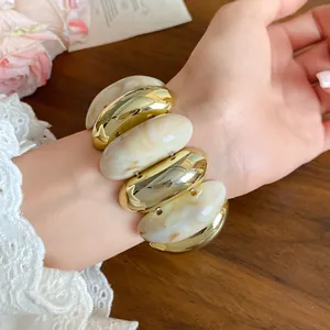 Detailed view of a chunky acrylic marbled elliptical bracelet with vintage gold finish