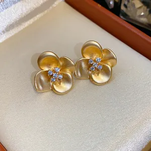 Detailed view of matte gold flower stud earrings with sparkling pave zircon in jewelry box