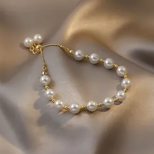 Elegant white pearl bracelet with gold bead accents on champagne satin fabric