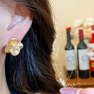 Close-up view of elegant French retro matte gold flower stud earrings with zirconia on ear