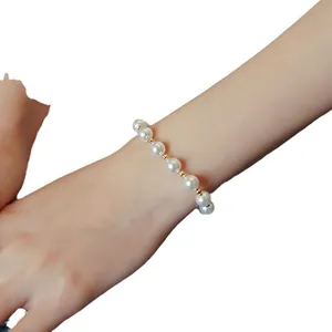 Elegant minimalist white pearl bracelet featuring small gold spacer beads worn on wrist