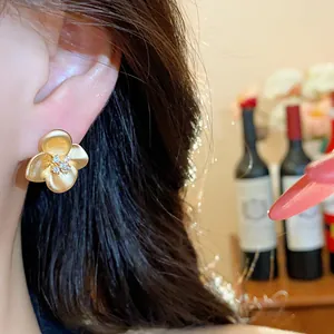 Close-up of an elegant gold-toned flower stud earring featuring sparkling zircon centers