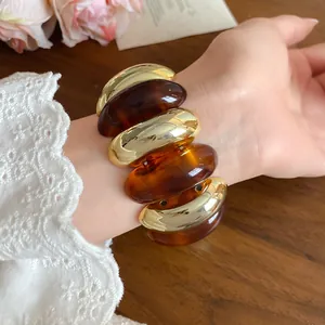 Close-up detail of a vintage amber acrylic and gold oval bead bracelet on a wrist