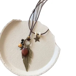 Handmade retro ethnic style necklace with bronze leaf and wooden beads on white tray.