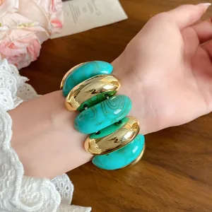 Macro view of chunky turquoise marbled and gold-tone oval link bracelet on a wrist