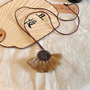 Macro detail of retro Chinese style necklace featuring beige tassels and wood bead accents
