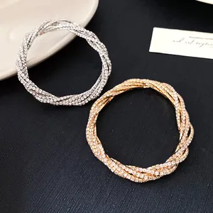 Detail view of gold and silver multilayer rhinestone wrap bracelets on a dark surface