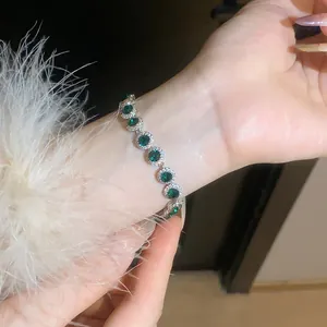 Close-up detail of luxury green zircon halo bracelet worn on wrist with elegant sleeve.