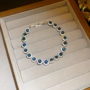 Close-up of shiny blue zircon round bracelet with halo stones in a jewelry tray.