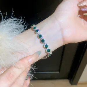 Close-up view of a green round zircon halo bracelet on a wrist with fuzzy sleeve