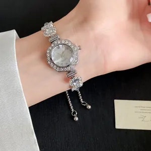 Gros plan d'une montre argentée pour femme avec lunette fleurie en strass et cordon