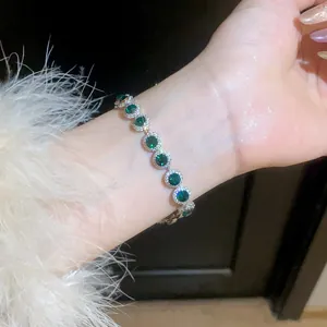 Detail view of an elegant silver bracelet featuring sparkling green round zircons on a wrist