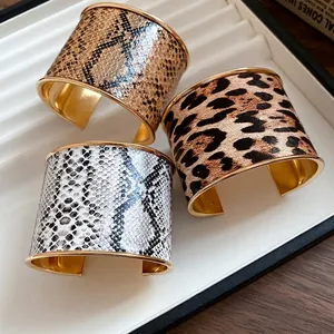 Wide golden cuff bracelets with leather animal prints including leopard and snakeskin