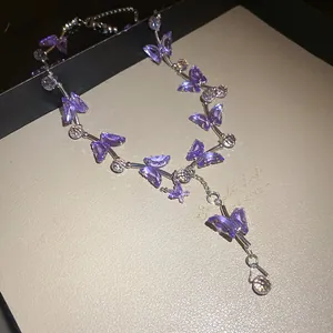 Detailansicht einer eleganten lila Schmetterlingshalskette aus Glas auf einer Box.