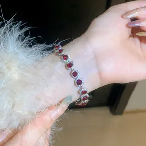Detailed close-up of a sparkling round red zircon bracelet with halo setting on a wrist