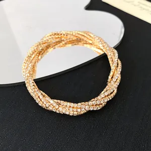 Detailed view of a luxury gold multi-layer rhinestone coiled bracelet on black background